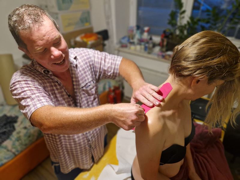 Aplikace kineziotapingu, Tomáš Kestner přikládá růžovou kineziopásku na trapézový sval klientky